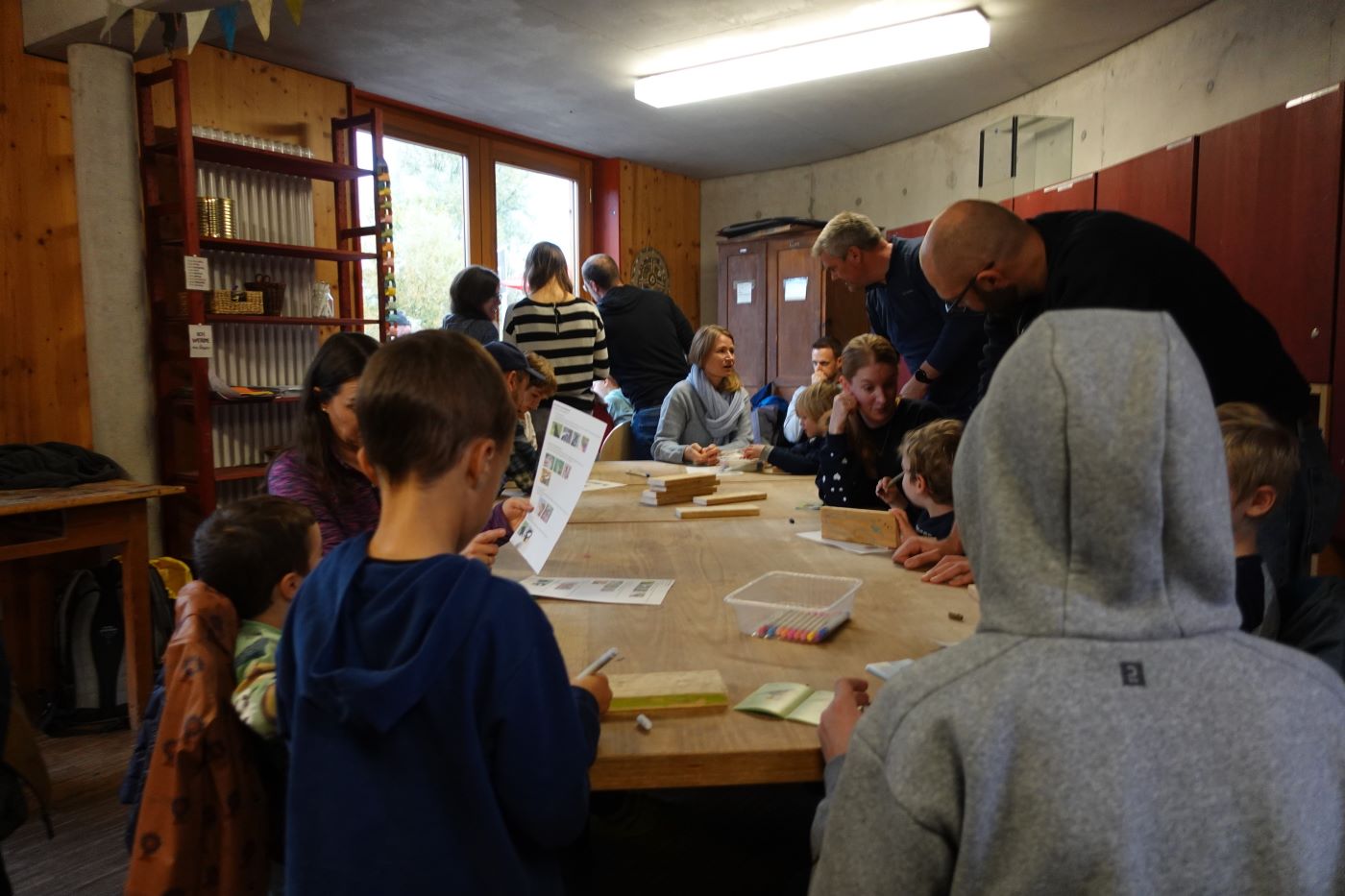 Kinder und Begleitpersonen arbeiten gemeinsam an einem großen Werktisch im Naturschutzzentrum Bergstraße.